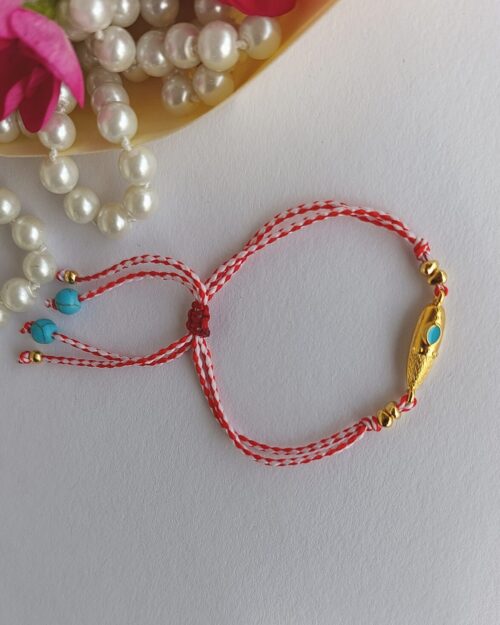 Χειροποίητο μαρτάκι με μεταλλικό μακρόστενο στοιχείο σε χρυσή απόχρωση με τυρκουάζ σμάλτο στο κέντρο.